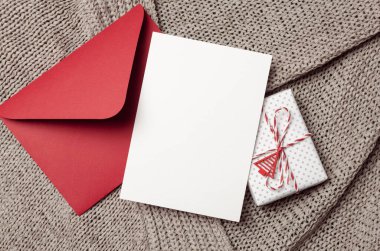 Noel veya Yeni Yıl tebrik kartı maketi hediye kutusu ve kırmızı zarf örülmüş arka planda