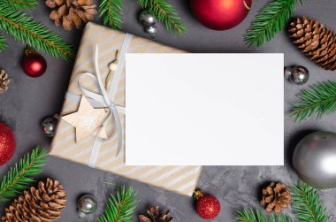 Noel tebrik kartı maketi hediye, şenlikli süslemeler, köknar ağacı dalları ve koyu arkaplanda koniler