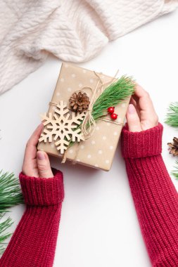 Süslü Noel hediye kutusunu beyaz arka planda tutan kadın elleri.