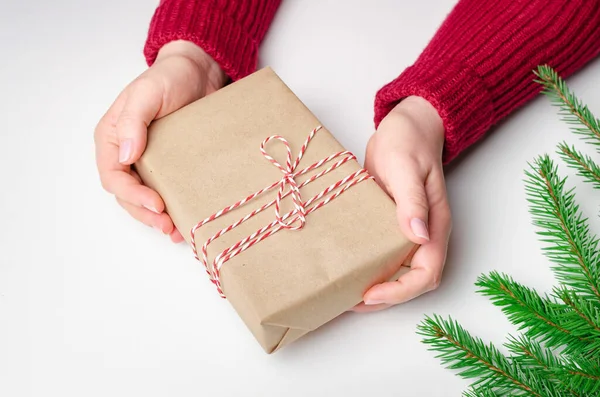 Christmas box w rękach kobiet na białym tle z gałązek jodły — Zdjęcie stockowe