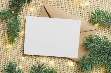 Noel tebrik kartı, çelenk ışıkları ve köknar ağacı dallarıyla örülmüş arka plan, üst görünüm