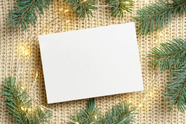 Noel tebrik kartı, çelenk ışıkları ve köknar ağacı dallarıyla örülmüş arka plan, üst görünüm