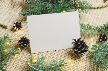 Noel ya da Yeni Yıl tebrik kartı modeli çelenk ışıkları ve örülmüş arka planda koni olan köknar ağacı dalları