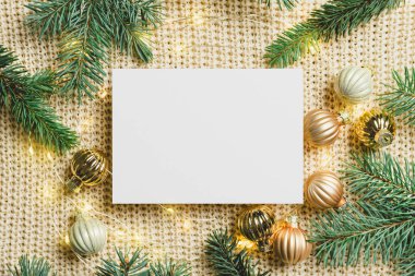 Noel tebrik kartı, çelenk ışıkları, balo süslemeleri ve örülmüş arka planda köknar ağacı dalları.