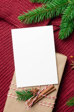 Noel ya da Yeni Yıl tebrik kartı modeliyle süslenmiş hediye kutusu ve kırmızı örgü arka planda köknar ağacı dalı