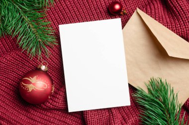 Mutlu noel tebrik kartı maketleri kırmızı toplar süslemeler ve örülmüş arka planda çam ağacı dalları