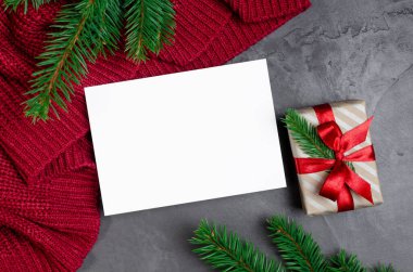 Noel tebrik kartı modeli hediye kutusu ve köknar ağacı dalları kırmızı örgü arka planda.