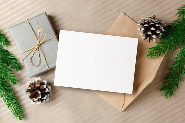 Świąteczne kartki makieta z kopertą, pudełko prezentów i gałązki jodły i szyszki dekoracje — Zdjęcie stockowe