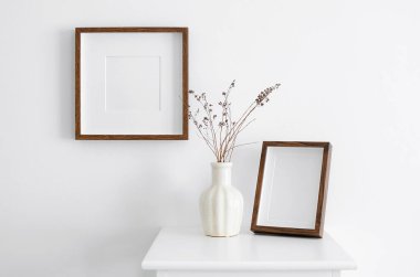 Resim, fotoğraf ya da baskı sunumu için iki portre ve kare ahşap çerçeve fotokopi alanı. Minimalist iç tasarım, beyaz duvar ve vazo dekorasyonu.