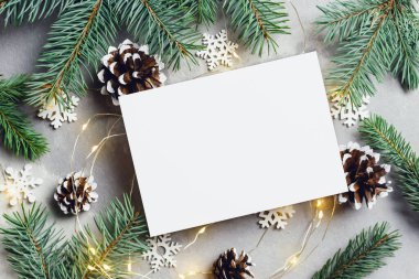 Noel veya Yeni Yıl tebrik kartı modeliyle köknar ağacı dalları koni ve çelenk ışıkları, üst görünüm