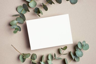 Greeting or wedding invitation card mockup with eucalyptus twigs. Empty card with copy space.