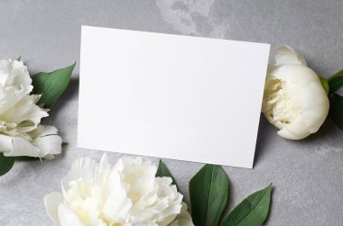 Greeting or invitation card mockup with copy space and white peony flowers on grey, mothers day concept