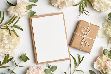 Davetiye ya da tebrik kartı modeli zarf, hediye kutusu ve beyaz şakayık çiçekleri ve beyaz okaliptüs dalları.