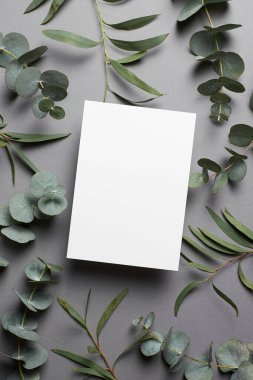 Wedding invitation or greeting card mockup with natural eucalyptus twigs. Card mockup with copy space.