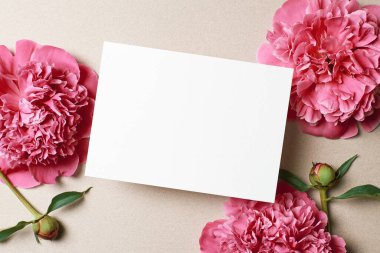 Kağıt arkaplanda pembe şakayık çiçekleri olan tebrik ya da davet kartı modeli, üst görünüm