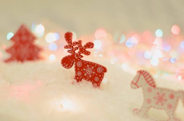 Yeni yıl kartı. Parlak ışıklar, kar, geyik figürleri, atlar ve köknar ağaçları..