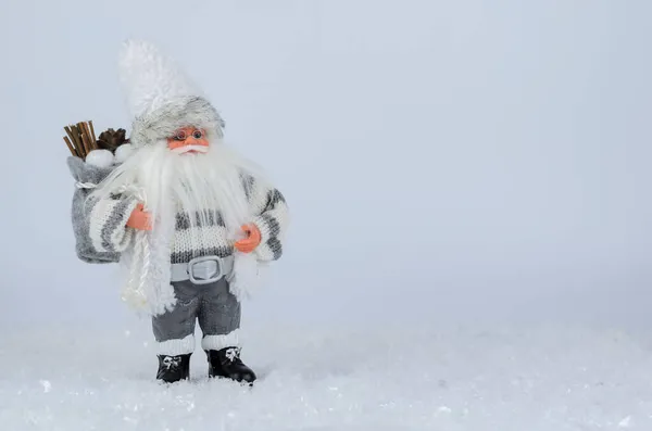 Santa Claus figurine standing in the snow on a white background. White and gray shades. — Stock Photo, Image