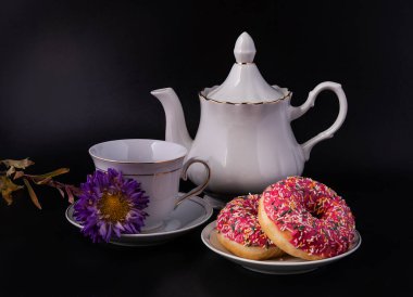 Sabah kahvaltısı için siyah arka planda çörekler ve çay seti..