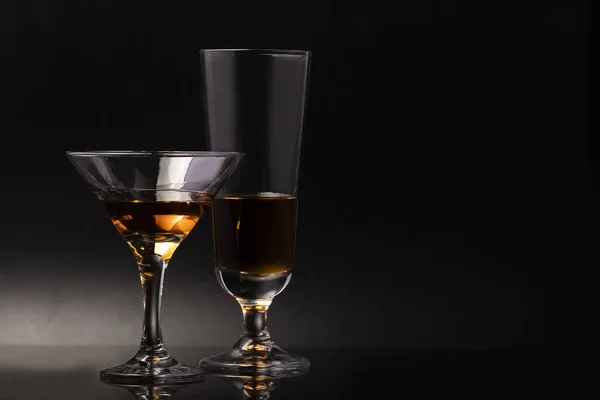 黒を基調としたアルコール飲料付きの美しい脚の上に2つのガラスグラス — ストック写真
