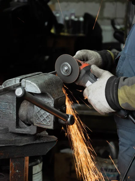 Sakallı bir adamın ellerinde öğütme makinesi, her yöne doğru parlak kıvılcımlar uçuşuyor..