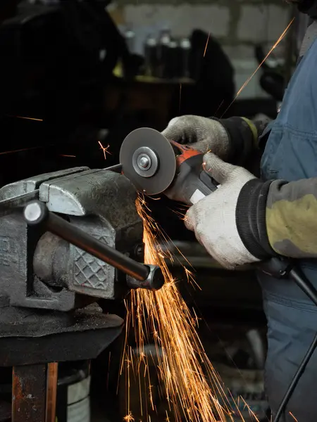 Sakallı bir adamın ellerinde öğütme makinesi, her yöne doğru parlak kıvılcımlar uçuşuyor..