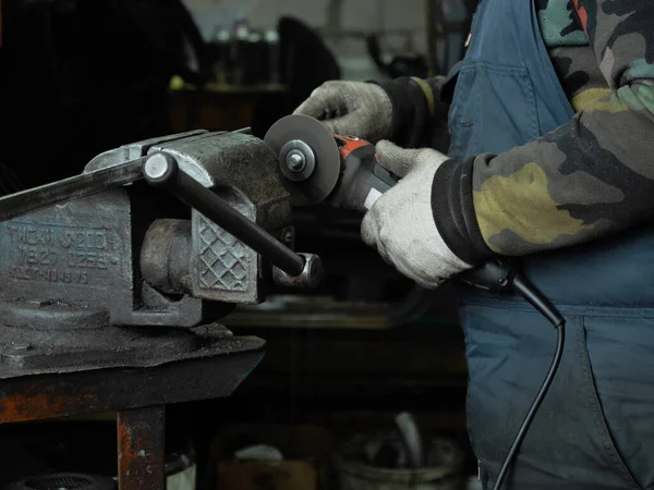 Sakallı bir adamın ellerinde öğütme makinesi, her yöne doğru parlak kıvılcımlar uçuşuyor..