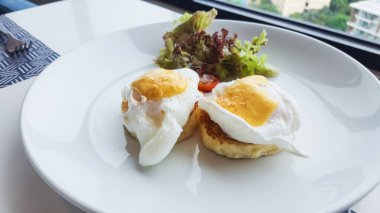 Masadaki beyaz tabağın üzerinde Benedict yumurtası