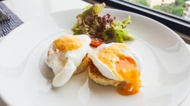 Masadaki beyaz tabağın üzerinde Benedict yumurtası