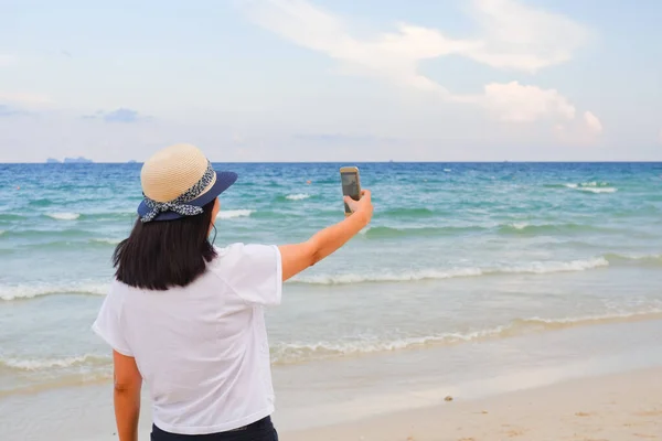Young asian woman selfie with smart phone on tropical beach