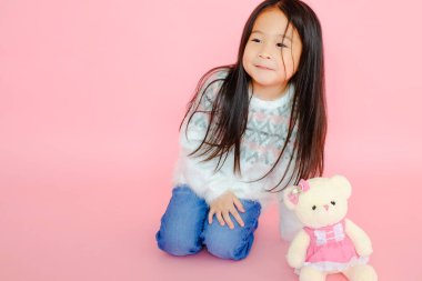 Pembe arka planda oyuncak ayıyla güzel Asyalı kız çocuğu portresi