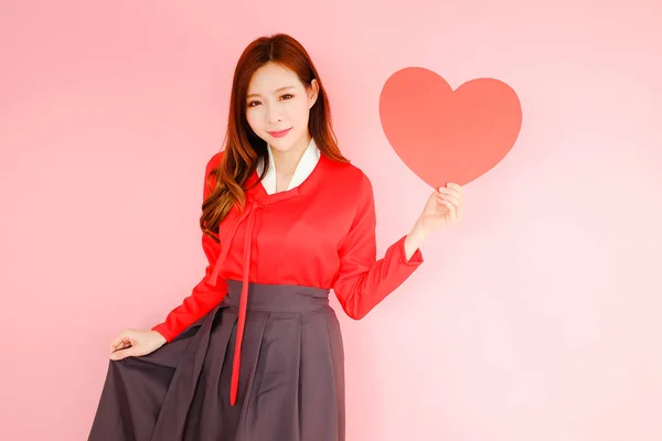 ピンクの背景に肖像美しいアジアの女性 愛の概念でバレンタインデー 手で赤いハートサインを保持モデル — ストック写真