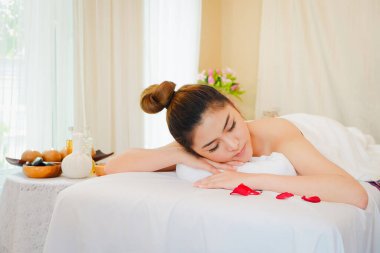 Genç Asyalı kadın spa masajında dinleniyor. Yatağa uzan.