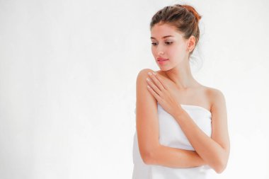 Güzel bir kadın beyaz havluyla yüzüne poz veriyor.