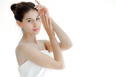 Güzel bir kadın beyaz havluyla yüzüne poz veriyor.