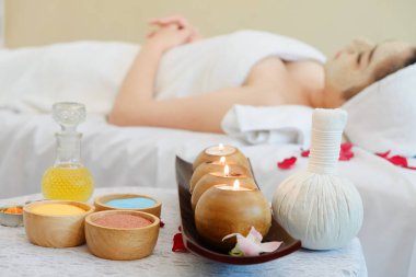 Spa kompozisyonu seti ve genç bir kadın yatakta uzanıyor ve masaj odasında dinleniyor, odaklanmayı seçin.