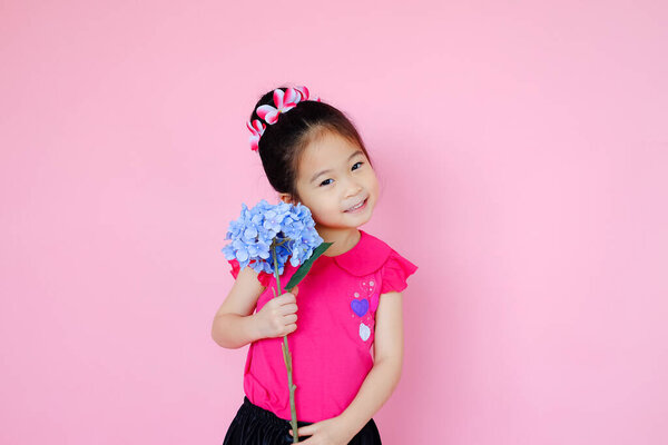 Маленькая милая азиатская маленькая девочка на розовом фоне с цветочным букетом