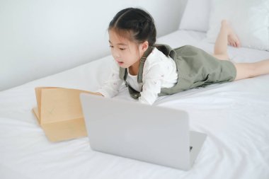 Asyalı küçük kız evde internetten öğreniyor.