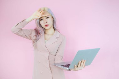 Asyalı iş kadını portresi. İnsanlar pembe arka planda dizüstü bilgisayarla evden çalışıyorlar.