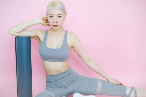 Paspas yogası, fitness sporları ve eğlence kavramı olan pembe arka planda güzel bir Asyalı kadın.