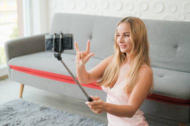 Seksi beyaz kadın elinde akıllı telefonuyla selfie çubuğu tutuyor.