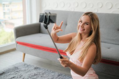 Seksi beyaz kadın elinde akıllı telefonuyla selfie çubuğu tutuyor.