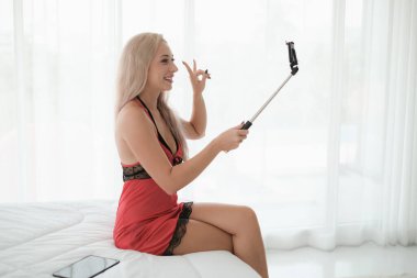Seksi beyaz kadın selfie çubuğu tutuyor ve işaret dili gösteriyor.