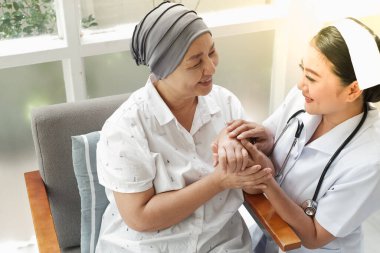 Asyalı kadın hemşireler evde yaşlı kadınlarla ilgilenirler.