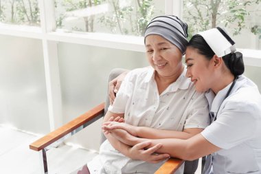 Asyalı kadın hemşireler evde yaşlı kadınlarla ilgilenirler.