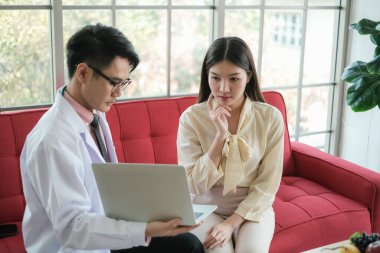 Profesyonel beslenme uzmanı Asyalı adam Asyalı kadına klinikte, hastanede ya da tıp kulübünde danışmanlık yapıyor.