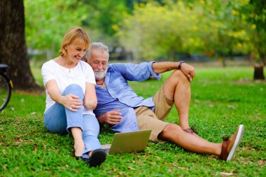 Kafkasyalı yaşlı kadın ve erkek portresi, parkta mutlu bir çift, sosyal medya ya da sosyal medya oyunu, dizüstü bilgisayar, online alışveriş.