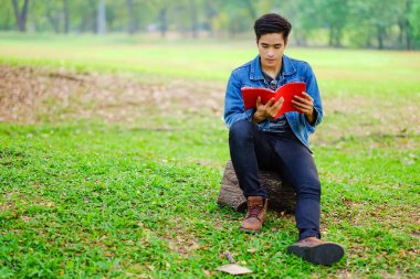 Asyalı adamın portresi parkta mutlu ve kitap okuyor.