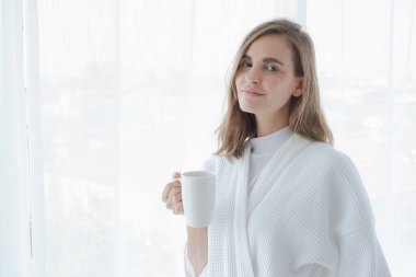 Kız sabahları pencerenin yanında sıcak kahve ya da çay içiyor.