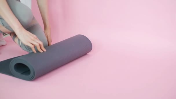 ピンクを背景にヨガマットを転がす若い女性の腕 — ストック動画