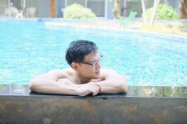 Asyalı adam yüzme havuzunda dinleniyor.
